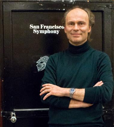 An image of Ragnar Bohlin standing in front of a black storage locker with the words "San Francisco Symphony" printed on it. 