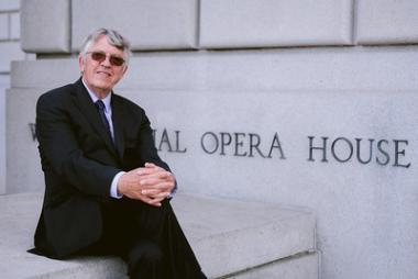 Ian Robertson wears a black suit, sitting outside of the War Memorial Opera House.