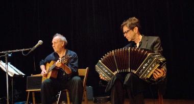 two men seated playing guitar and bandoneon