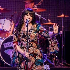 Gesenia holding her hand out with singing in a microphone as Linda Ronstadt.