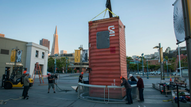 A shipping container, pitched vertically, serves as the "lungs" of the installation